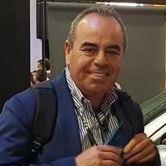 Joel Espinoza, sonriendo, con saco azul